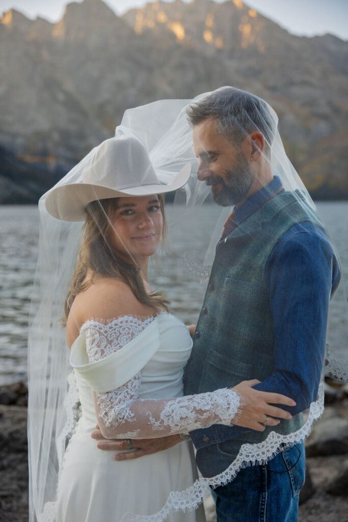 Bride looks at camera while groom admires her