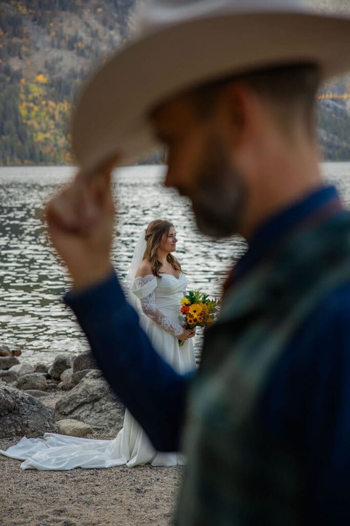 Bride is seen beyond groom as she looks at the sunset