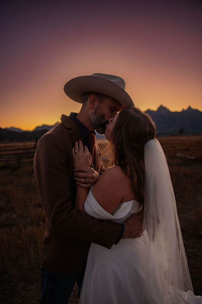 Bride and groom kiss at sunset