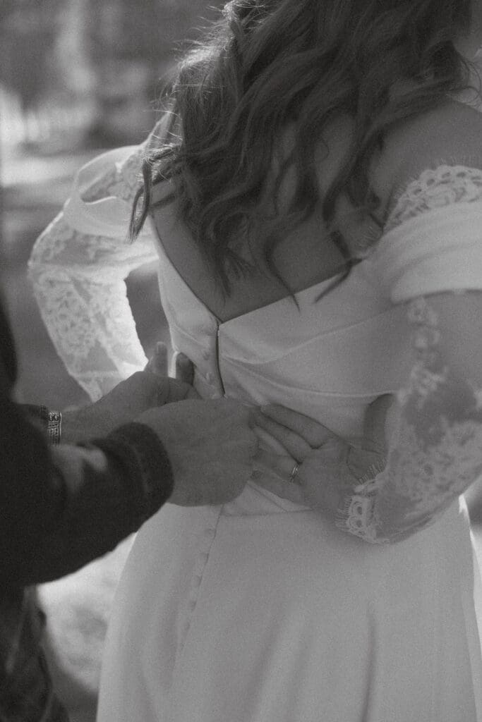 Groom helps bride zip up her dress