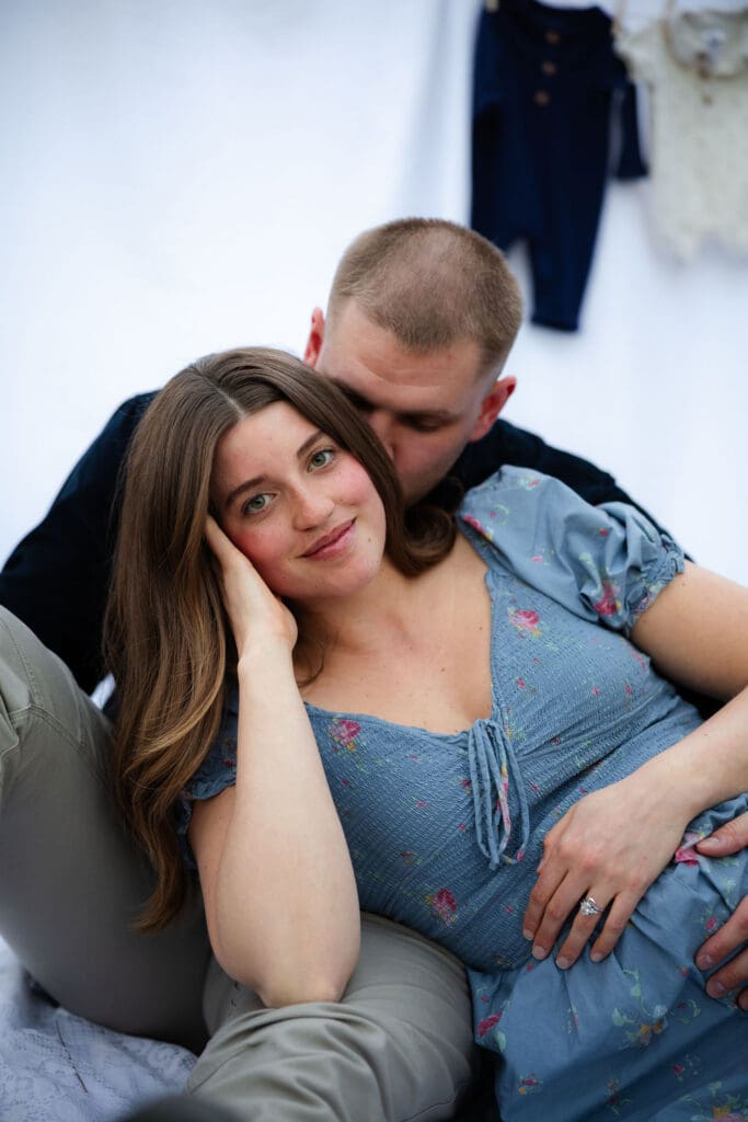 maternity couple snuggles on blanket