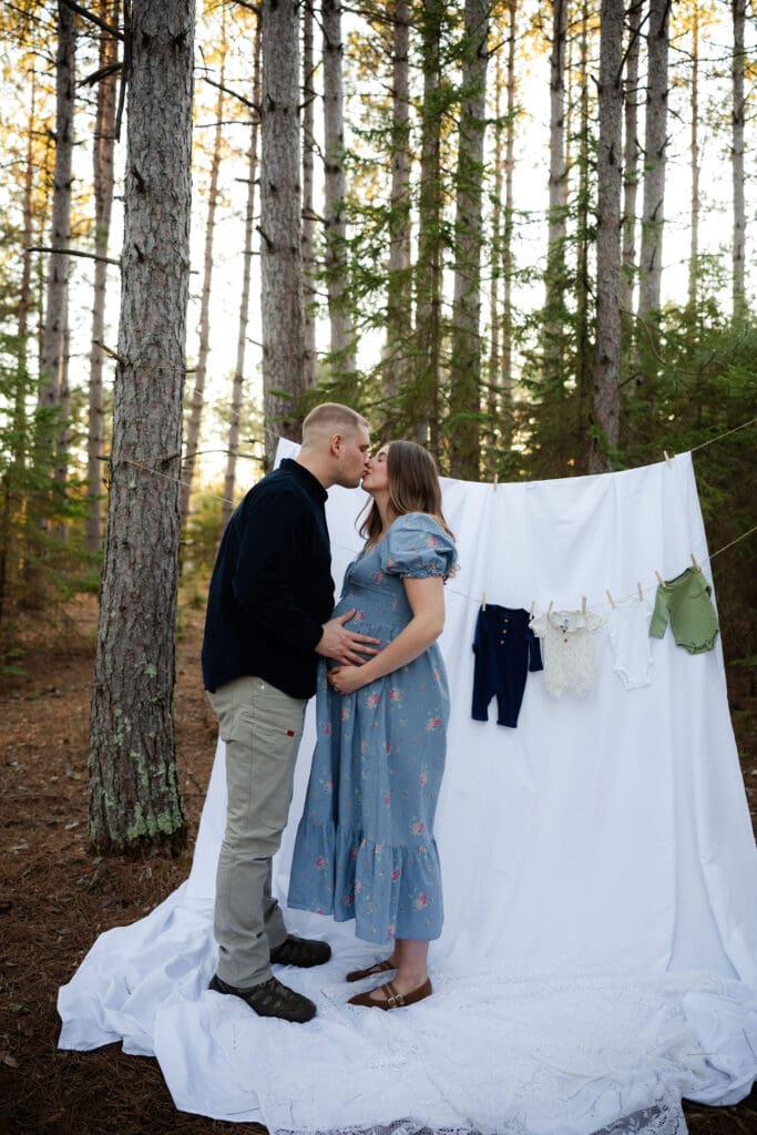 Maternity couples embraces in front of hanging sheet