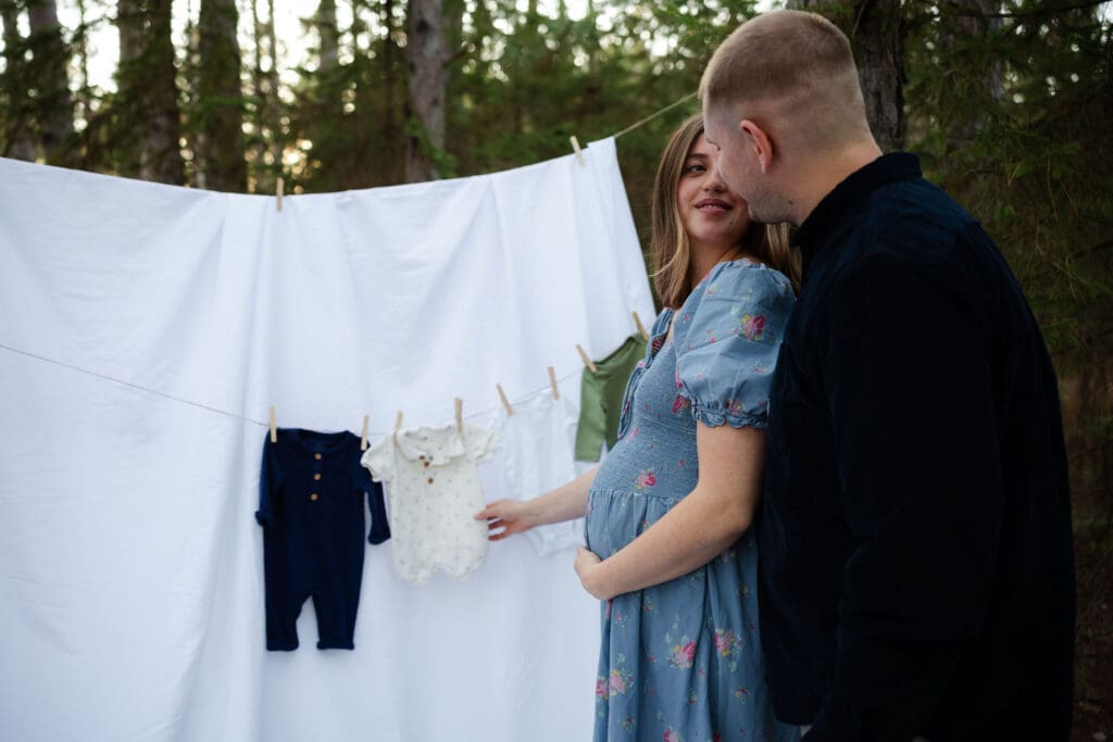maternity couple hang baby clothes 