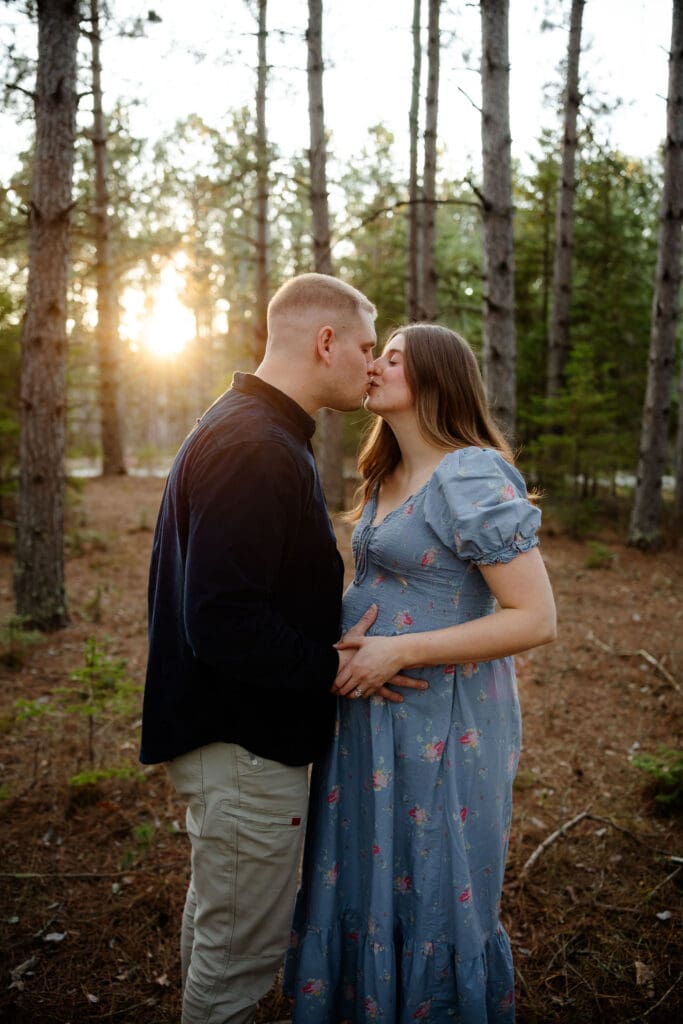 Maternity couple share a kiss during forest maternity session