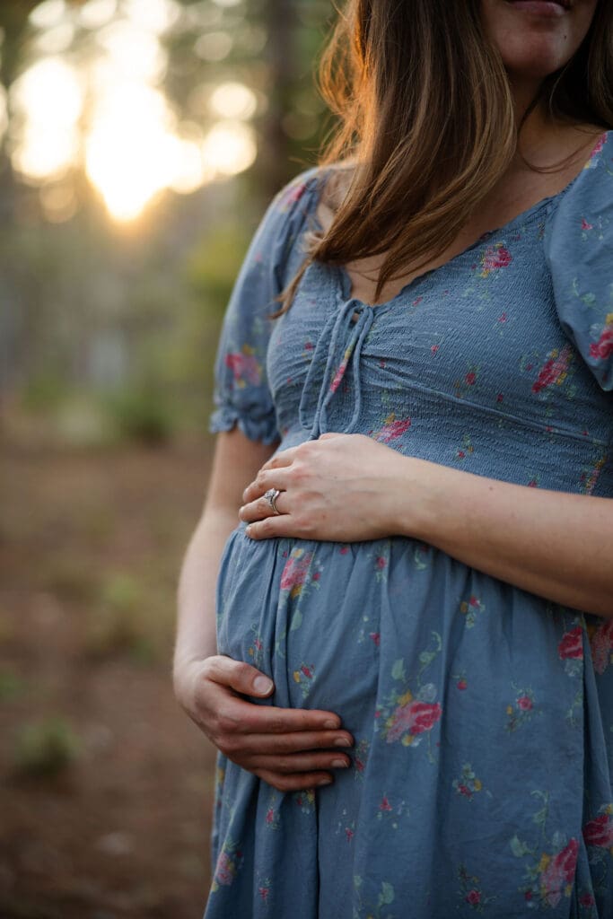 Pregnant mother embraces baby bump at sunset