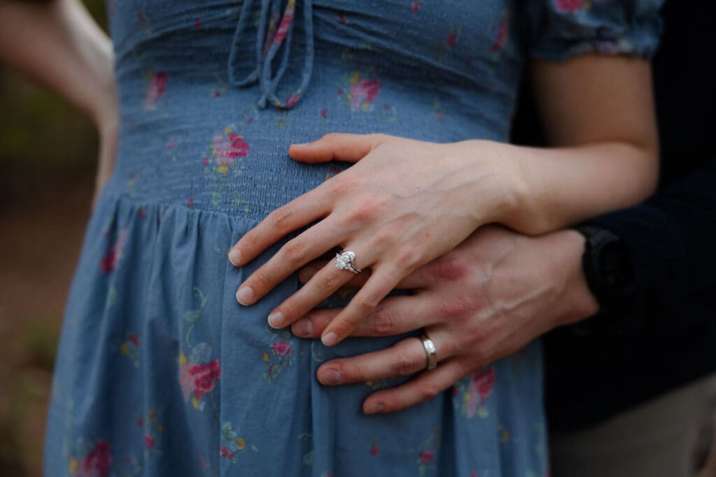Husband and wife place their rings on baby bump