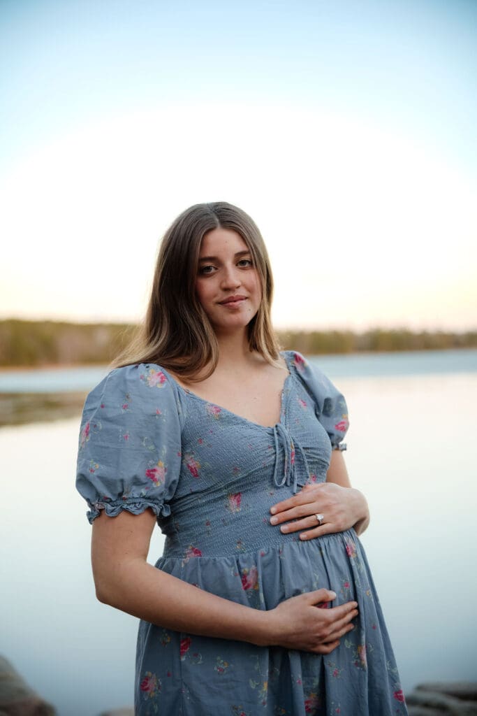 Pregnant mother smiles in front of frozen Lake Itasca