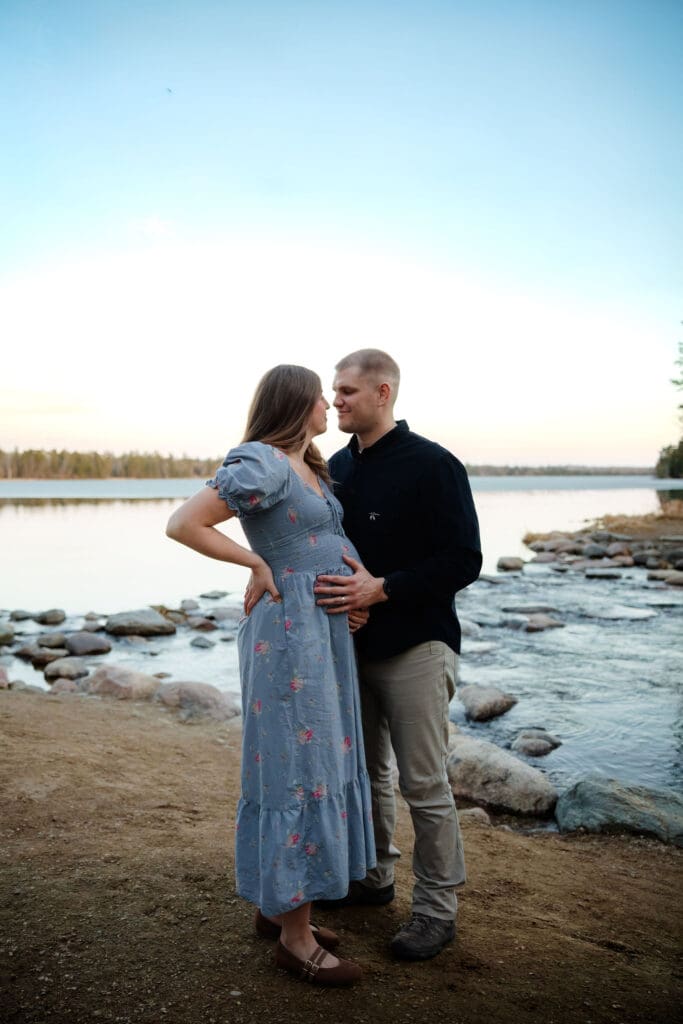 Itasca State Park maternity Session couples smiles for a photo at the headwaters of the Mississippi