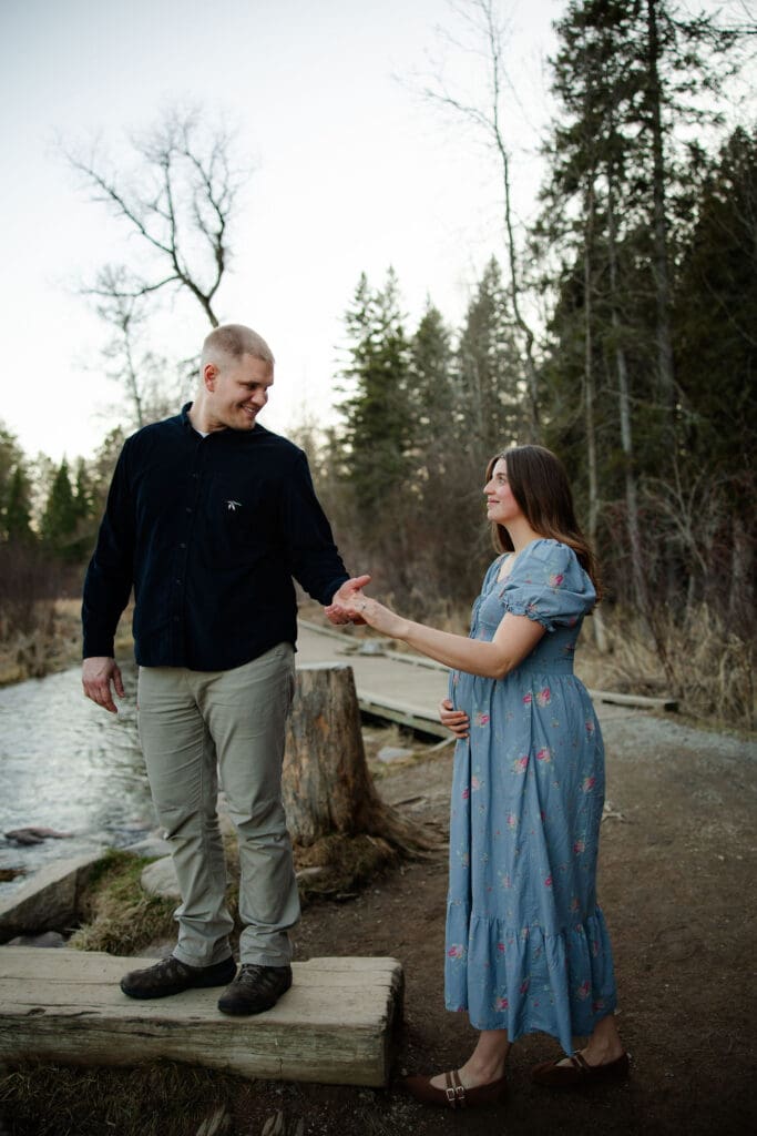 Husband helps pregnant wife onto a log bridge over the Mississippi River