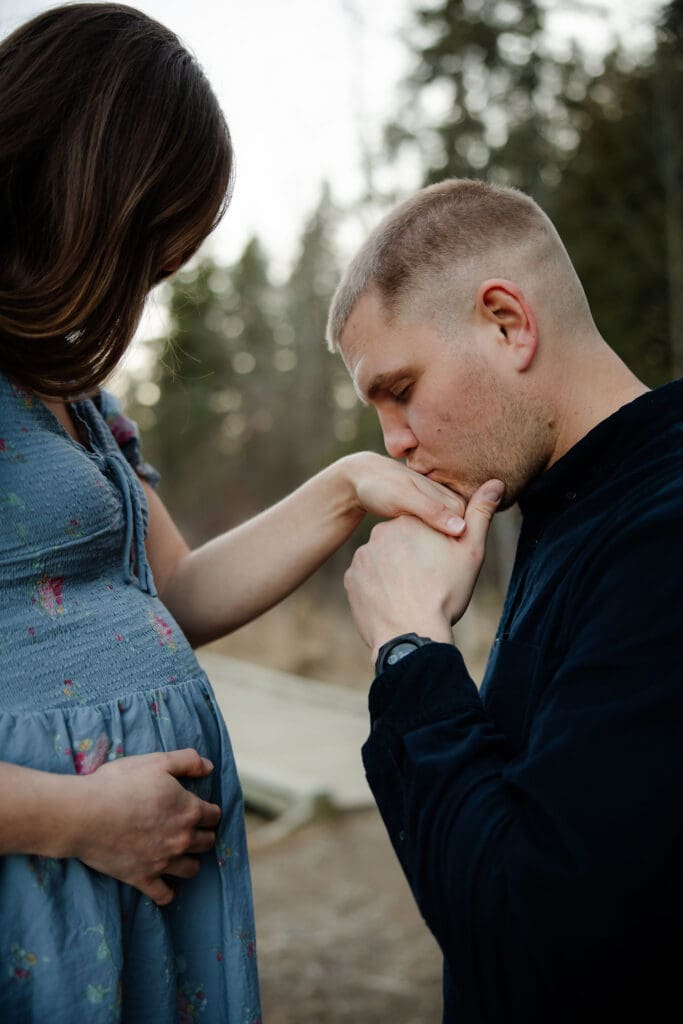 Husband kisses pregnant wife's hand at their maternity photo session