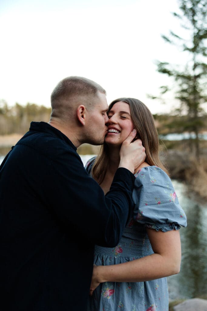 Husband and wife laugh together at their maternity session