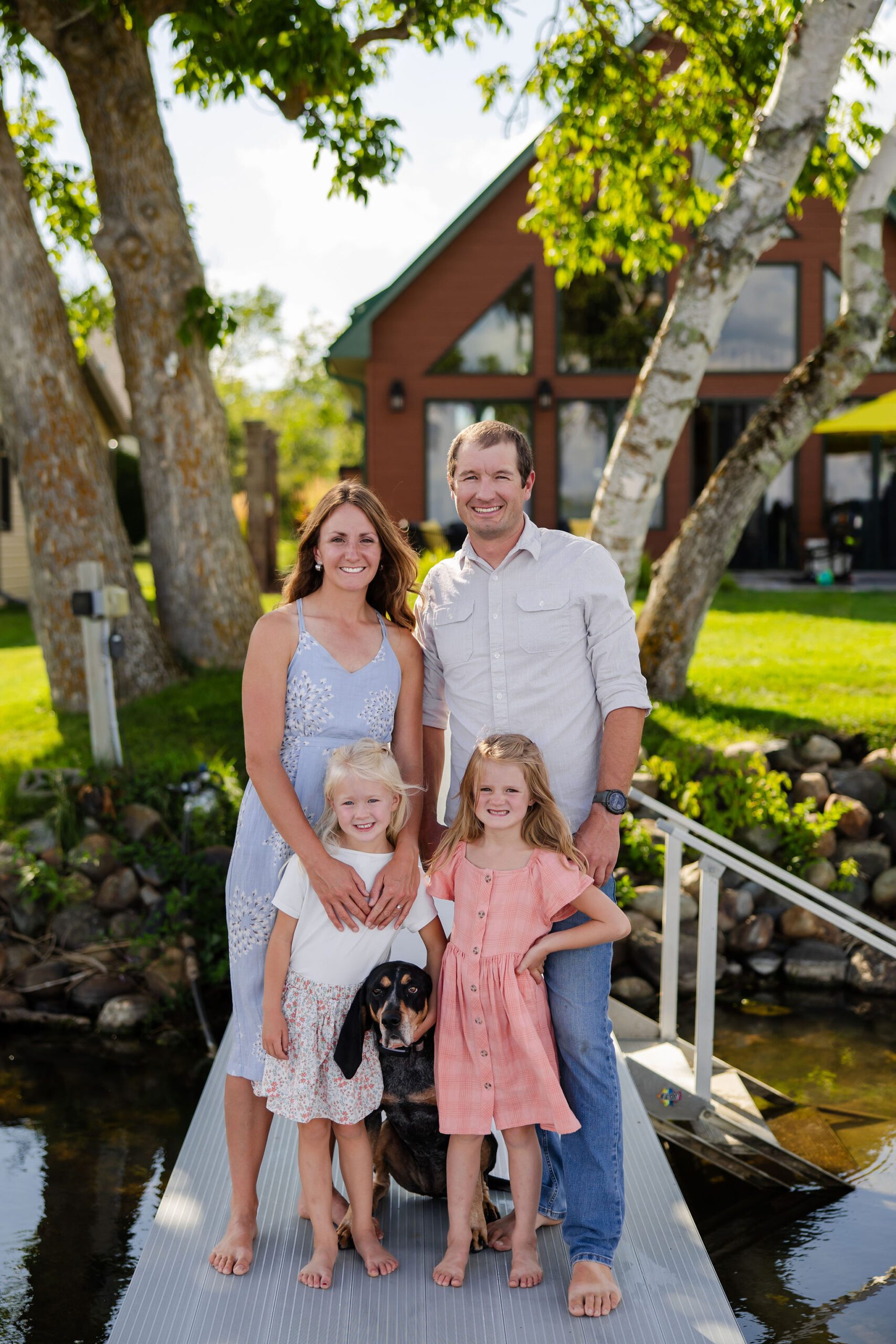 Family poses in front of cabin alongside family dog