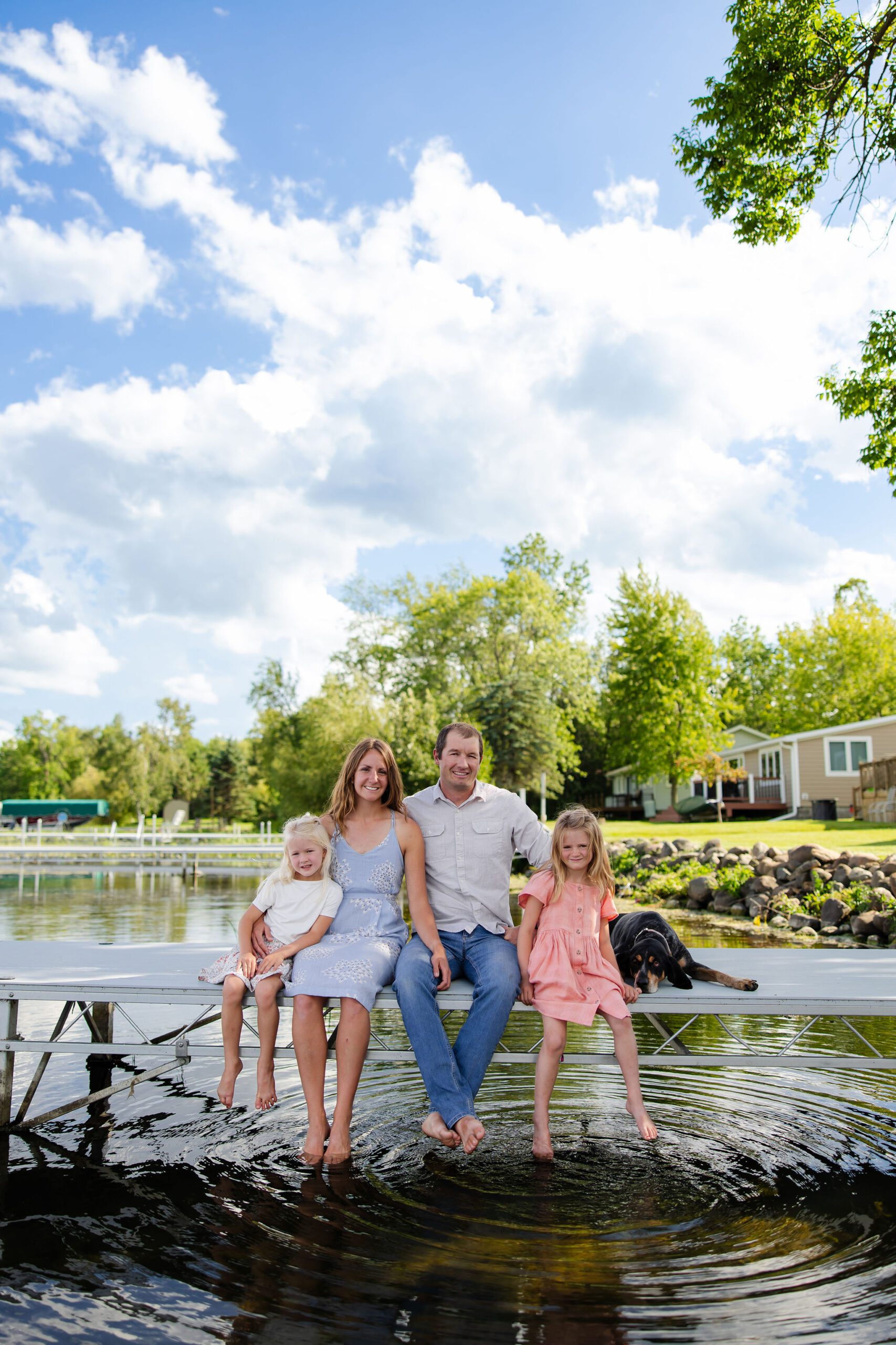 family sits on dock and splashes water for photo
