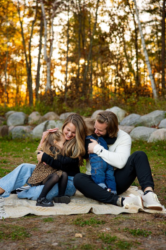 Family cuddles under fall foliage