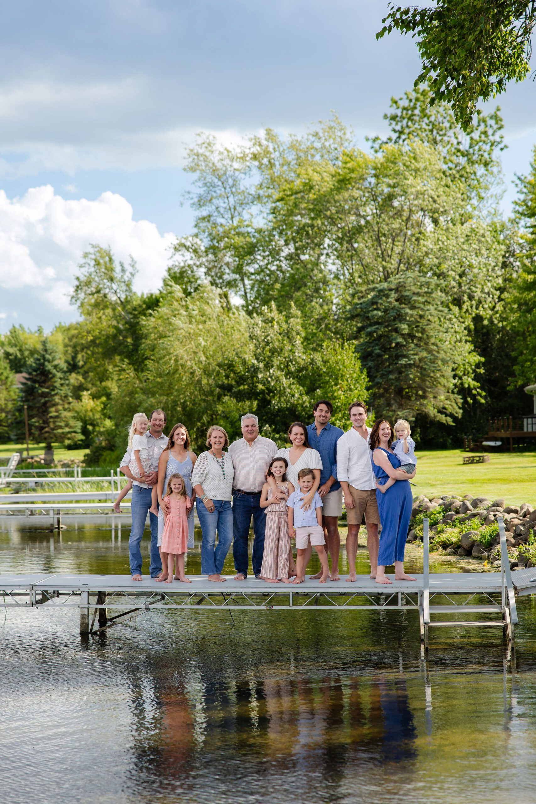 extended family smiles standing under blue skies